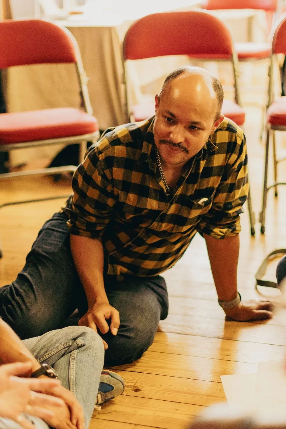 A smiling participant sitting on the floor during a group conversation