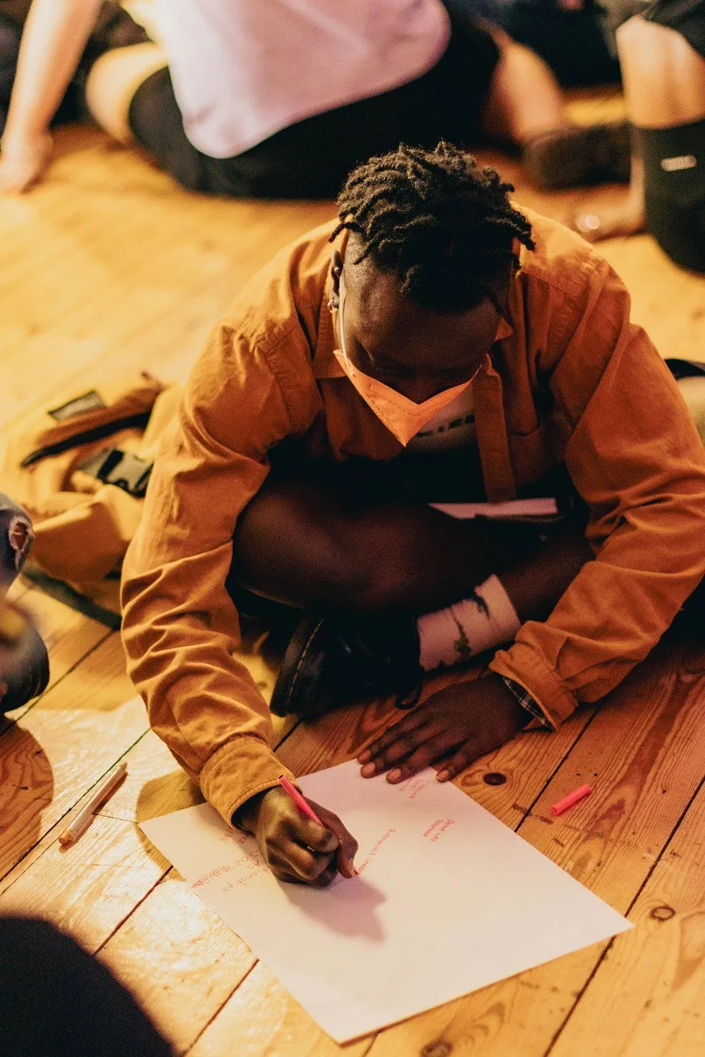 A participant writing on paper while sitting on the floor