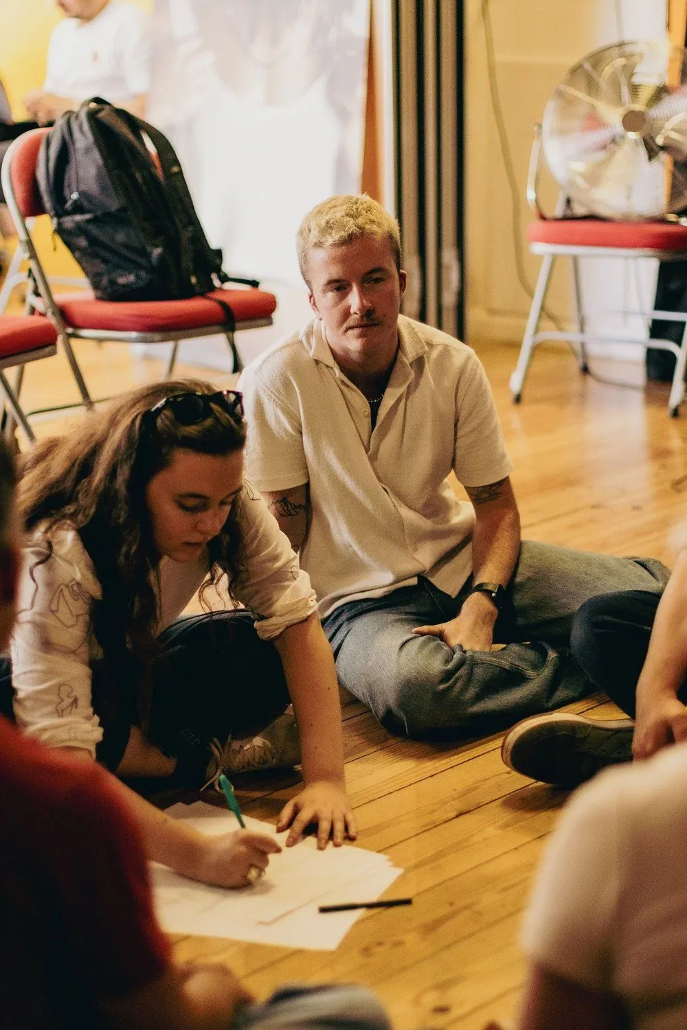 Two participants sitting together, one writing during a workshop exercise